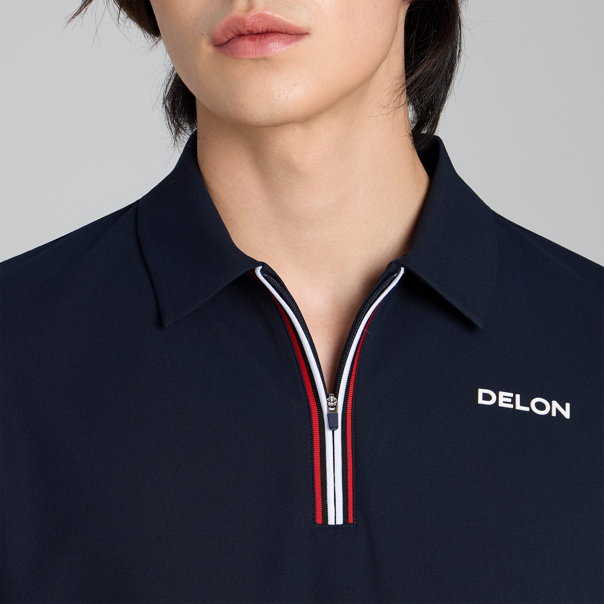 Navy blue polo shirt with a zipper and 'DELON' branding on a gray background