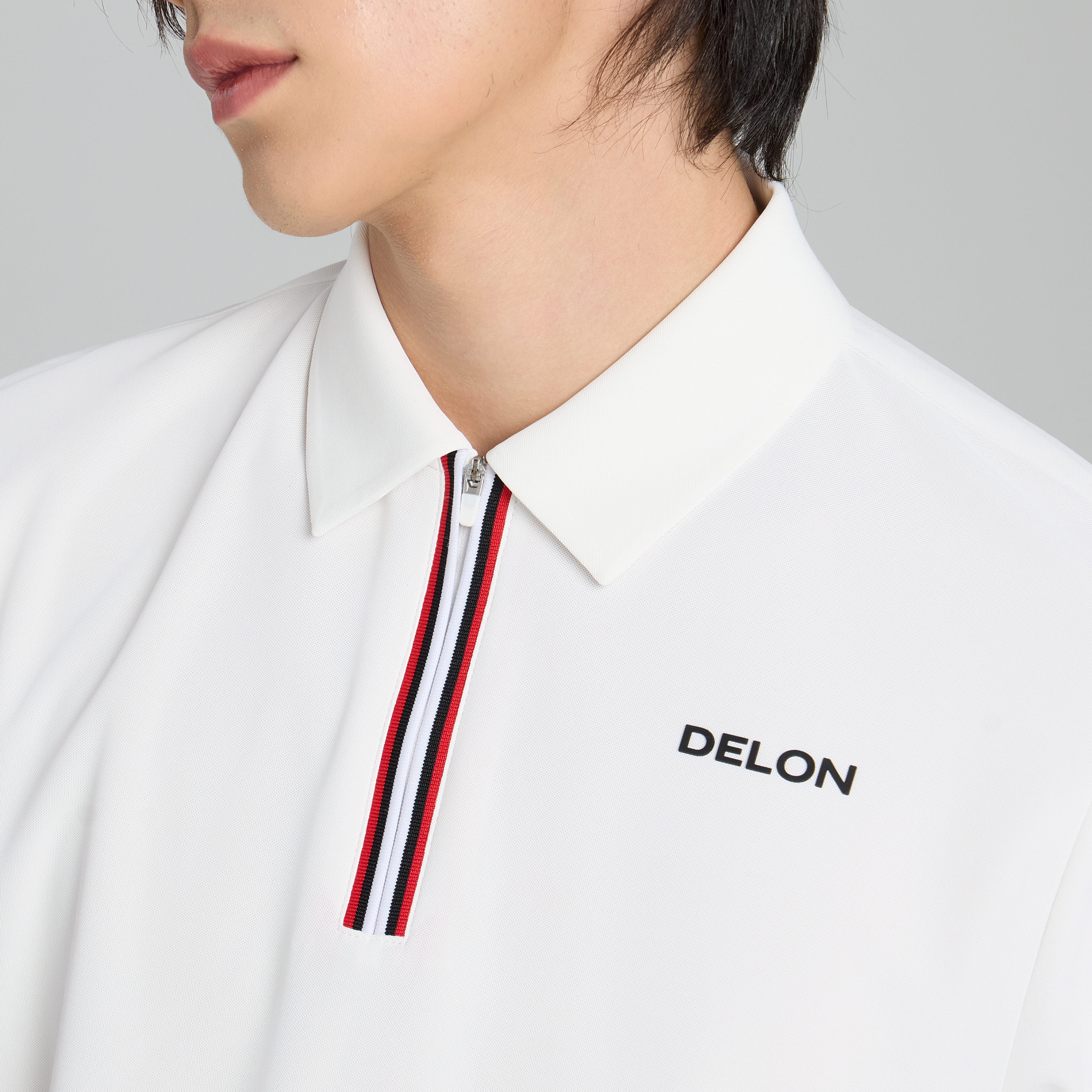 Close-up of the zipper placket and tailored classic collar on the DELON men's performance golf polo.